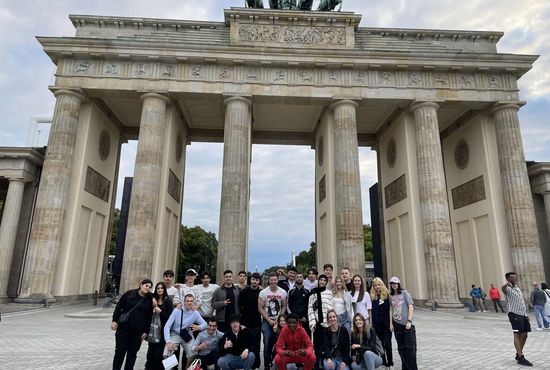 Eine Gruppe junger Menschen steht vor dem Brandenburger Tor in Berlin.